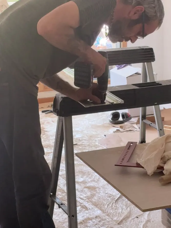 Un artisan IRGT découpe une pièce sur mesure sur des tréteaux